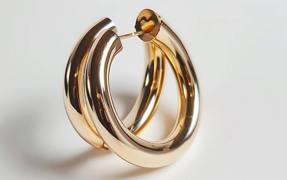 A pair of elegant, shiny gold hoop earrings with a smooth, polished finish, resting on a light background.