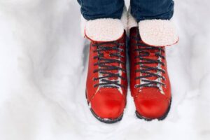 Close-up of red winter boots with a fluffy collar, standing in fresh white snow, conveying a cozy winter scene.